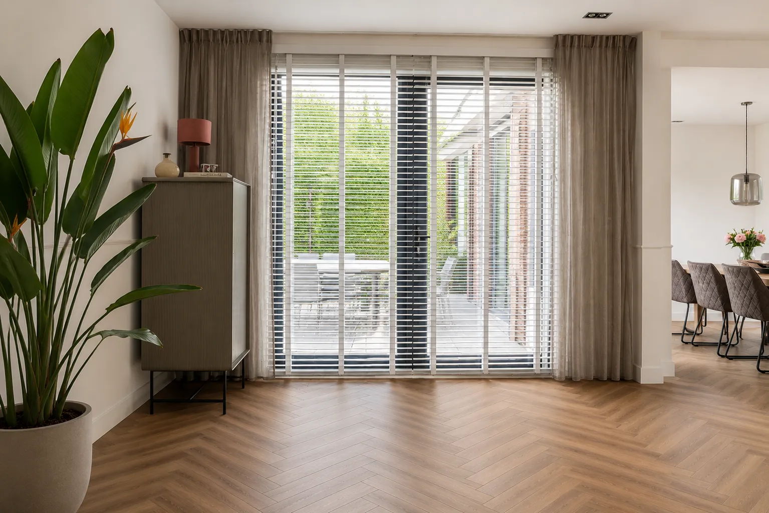 Witte houten jaloezieën voor de tuindeuren van een woonkamer