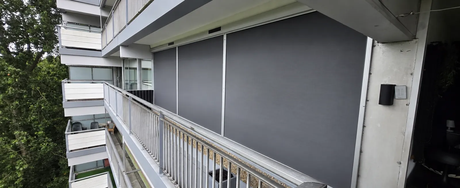 Gesloten ritsscreens met grijs doek over de volle breedte van een balkon