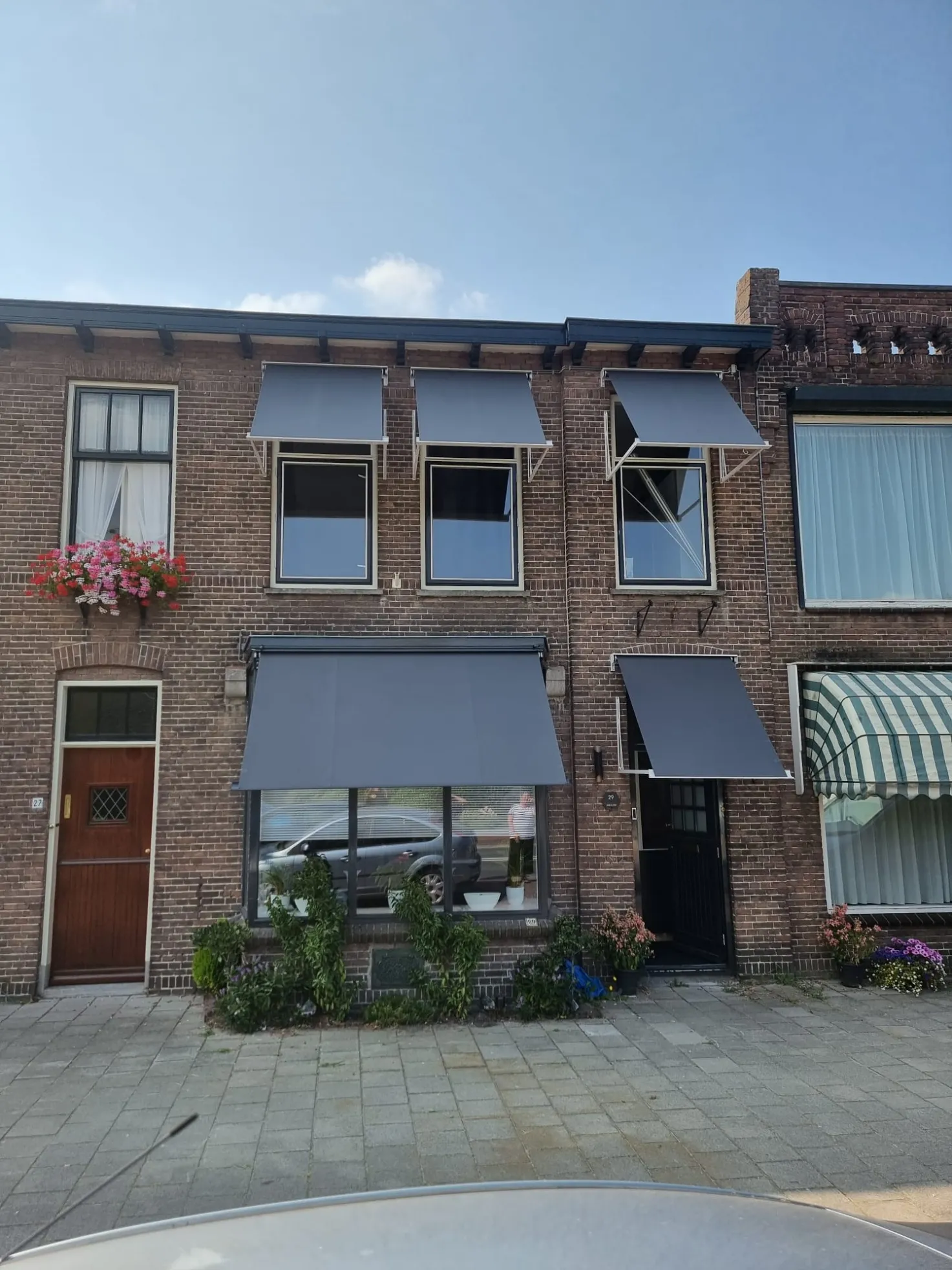 Grijze uitvalschermen boven de ramen op de eerste verdieping van een woonhuis