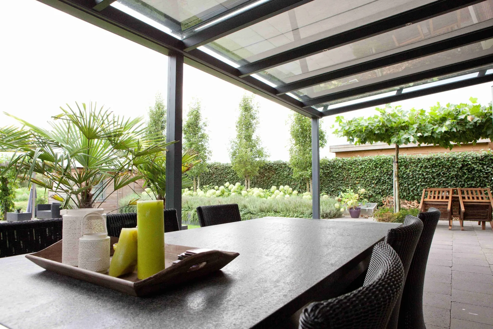Veranda met uitgerold zonweringsdoek onder het glazen dak