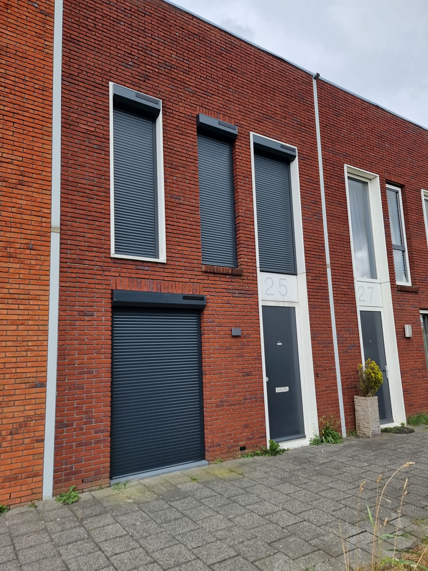 Drie gesloten rolluiken op een bakstenen gevel